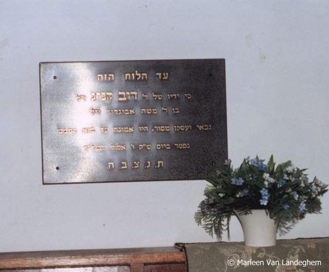 "Deze plaat getuigt dat wijlen Dov König, zoon van wijlen rabbijn Moshe Avigdor, toegewijd beheerder en bestuurder steeds aanwezig was tot aan het ondergaan van de Zon < ( = tot zijn laatste dag ) > . Hij is overleden de dag van de heilige Sabbat , de 6de Eloul 5734 < ( = 24 augustus 1974)> . Dat zijn ziel zou opgenomen worden in de bundel van het leven < ( = R.I.P )> " vert. J. Deom